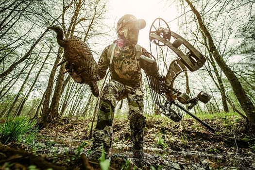 Hunter wearing Pnuma warm weather hunting clothes, including lightweight shirt and pants, glassing from a sunny ridge during an early season spot-and-stalk pursuit.