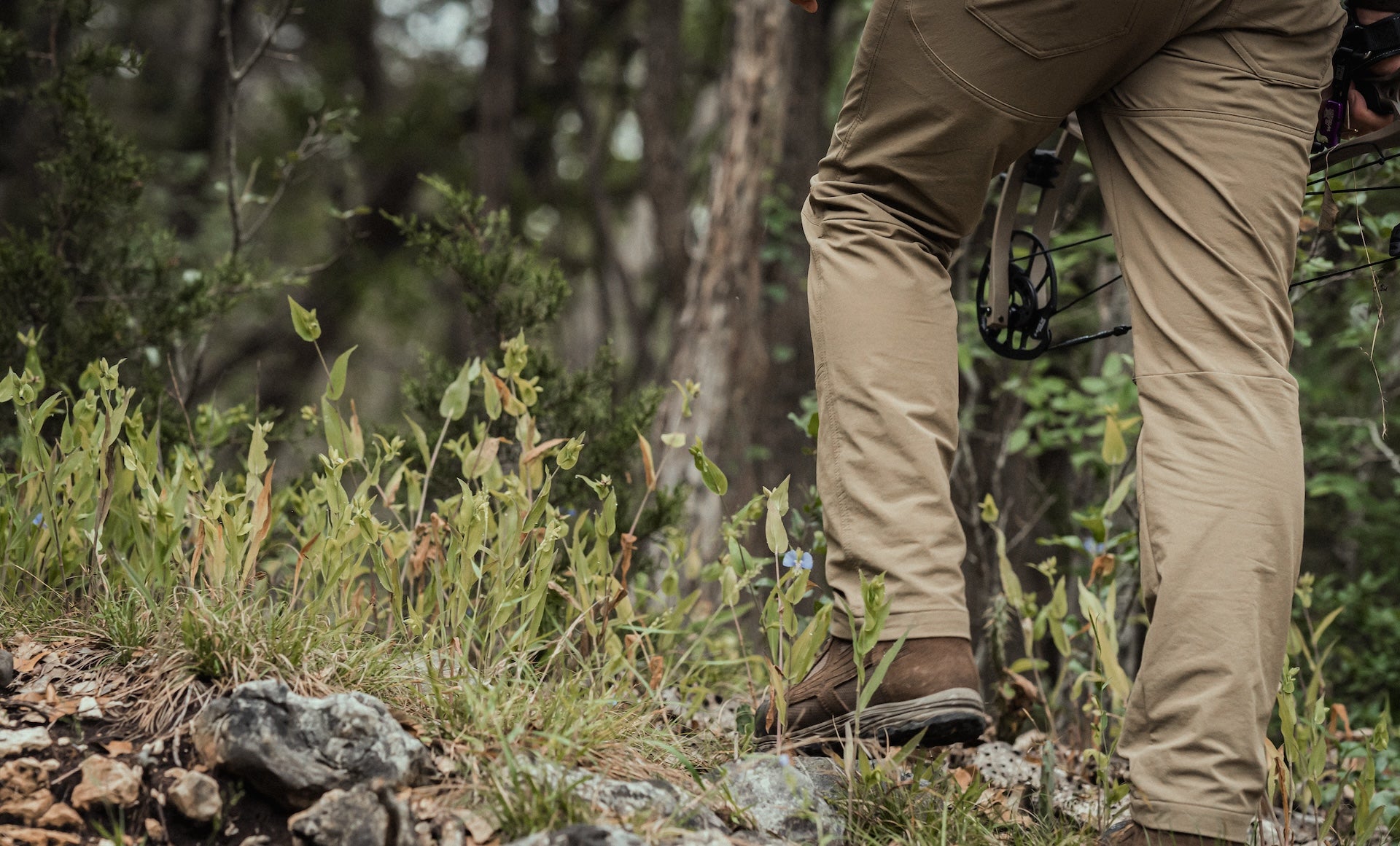 A man dressed in khaki pants and hiking boots stands outdoors, ready for an adventure.
